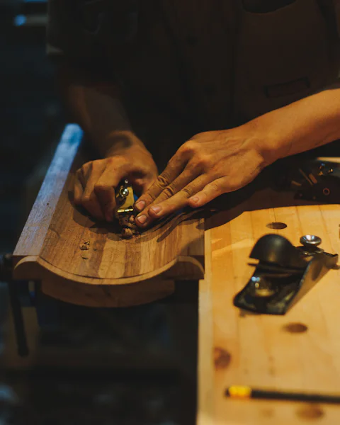 Les mains d'un artisan qui rabotent une pièce de bois